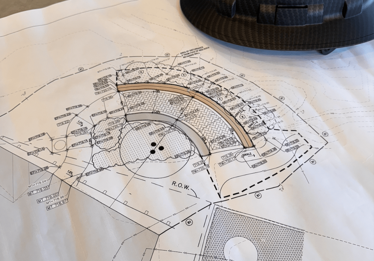 Construction Management Cover Photo-min A GRID26 branded hardhat sitting on the blueprints for a construction project.